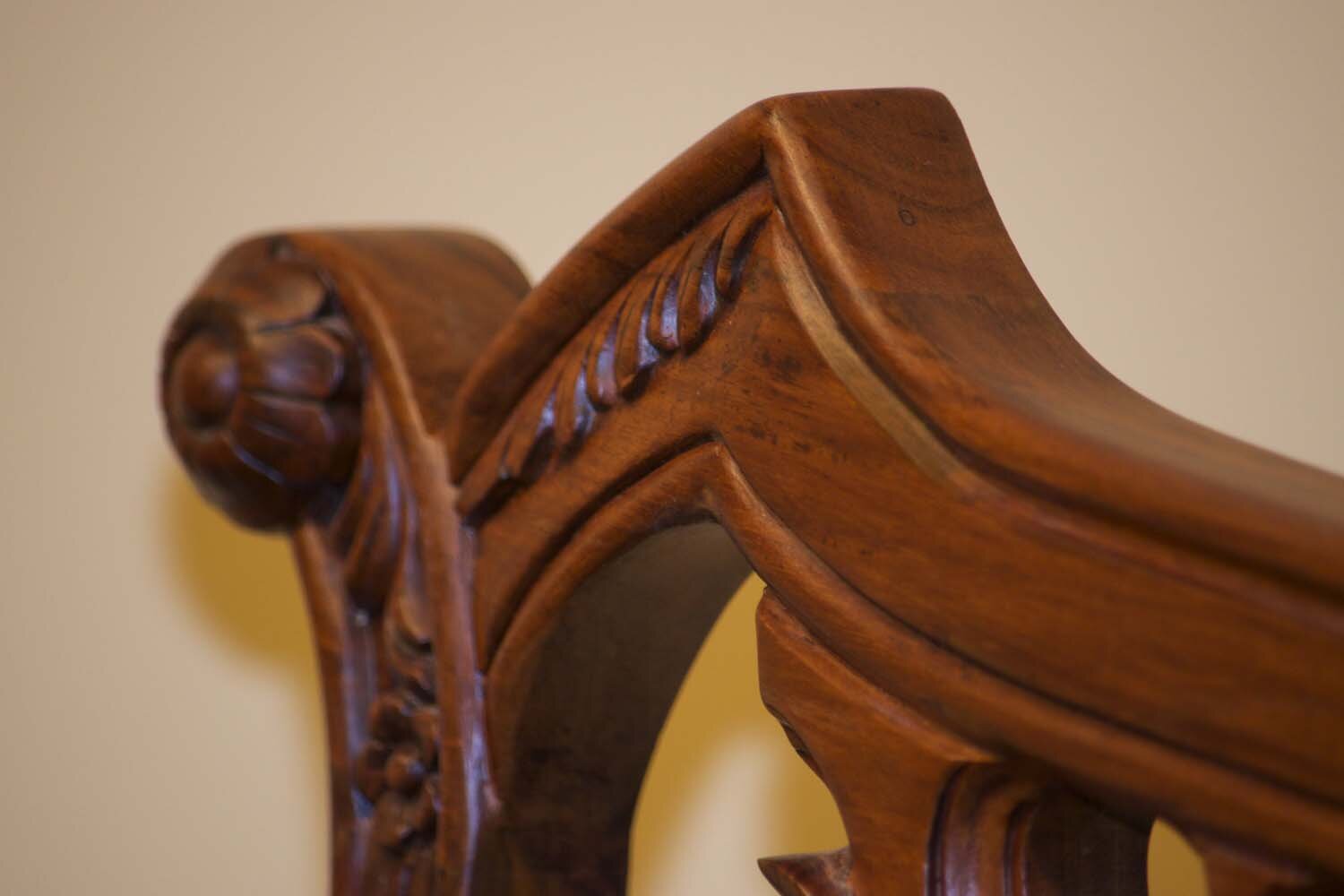 Close-up of the chair’s hand-carved rosewood crest rail featuring floral and scroll motifs